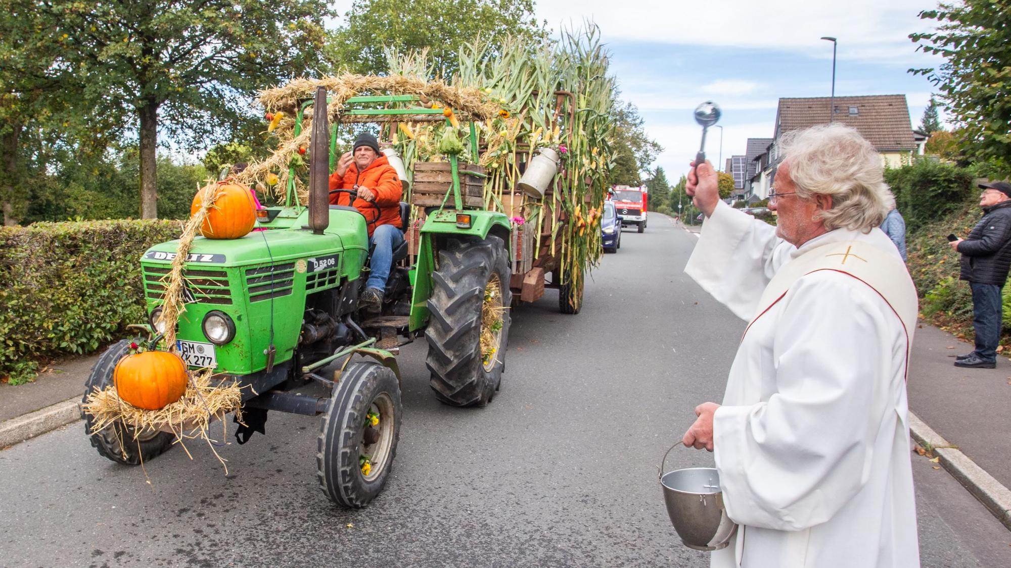 Ein Diakon spendet einem Erntewagen den Segen.