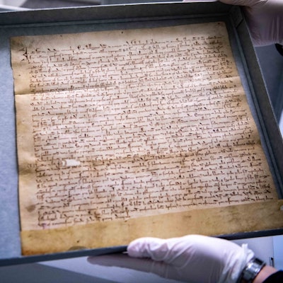 Zwei Hände in weißen Handschuhen halten die originale Stadtrechtsurkunde von Euskirchen.