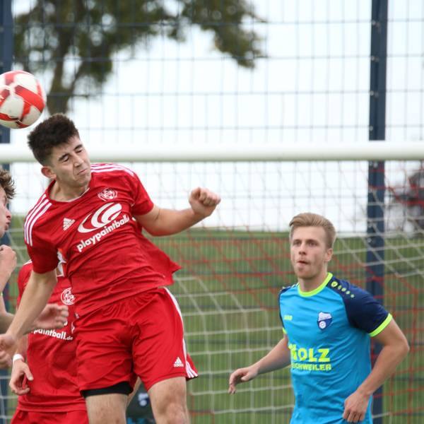 Zwei Spieler steigen zum Kopfballduell hoch, ein anderer beobachtet die Szene.