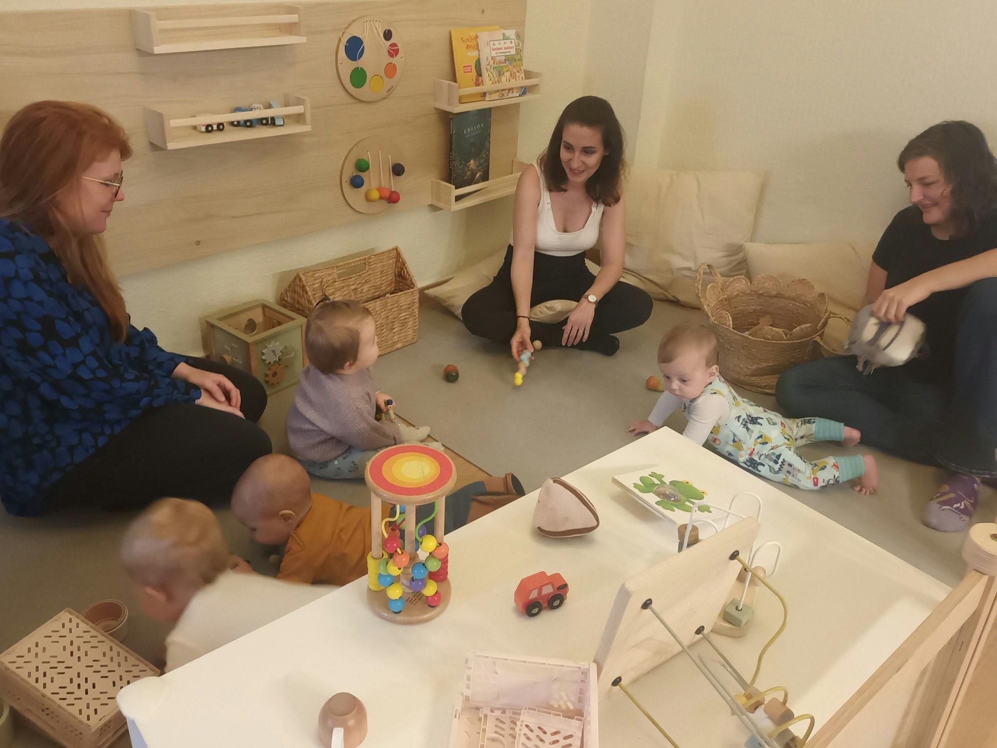 Drei Mütter und vier Krabbelbabys in der Spielecke eines Cafés
