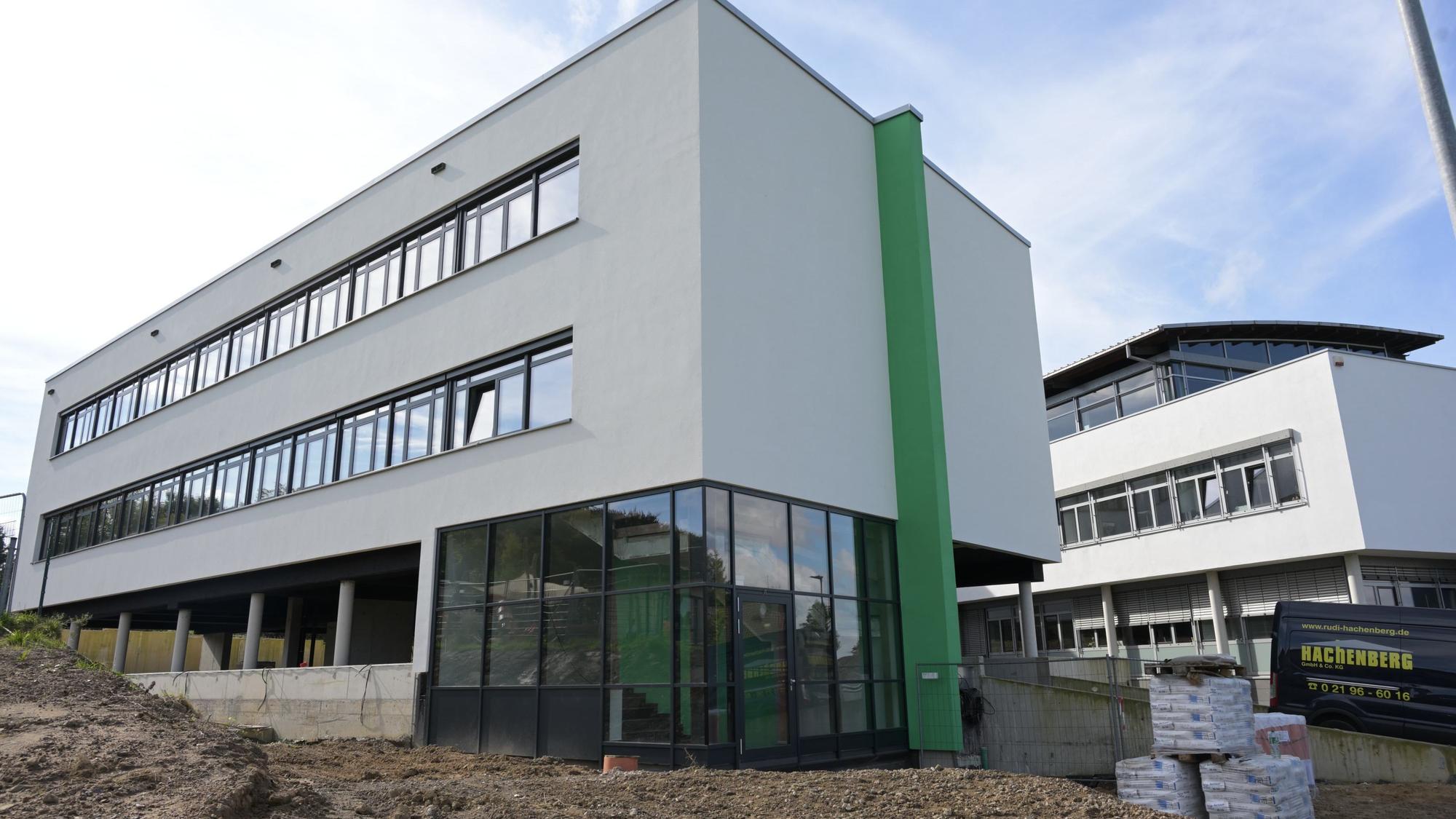 Im Vordergrund steht der Neubau, noch zwischen Erdhügeln. Im Hintergrund ist der Altbau zu sehen.