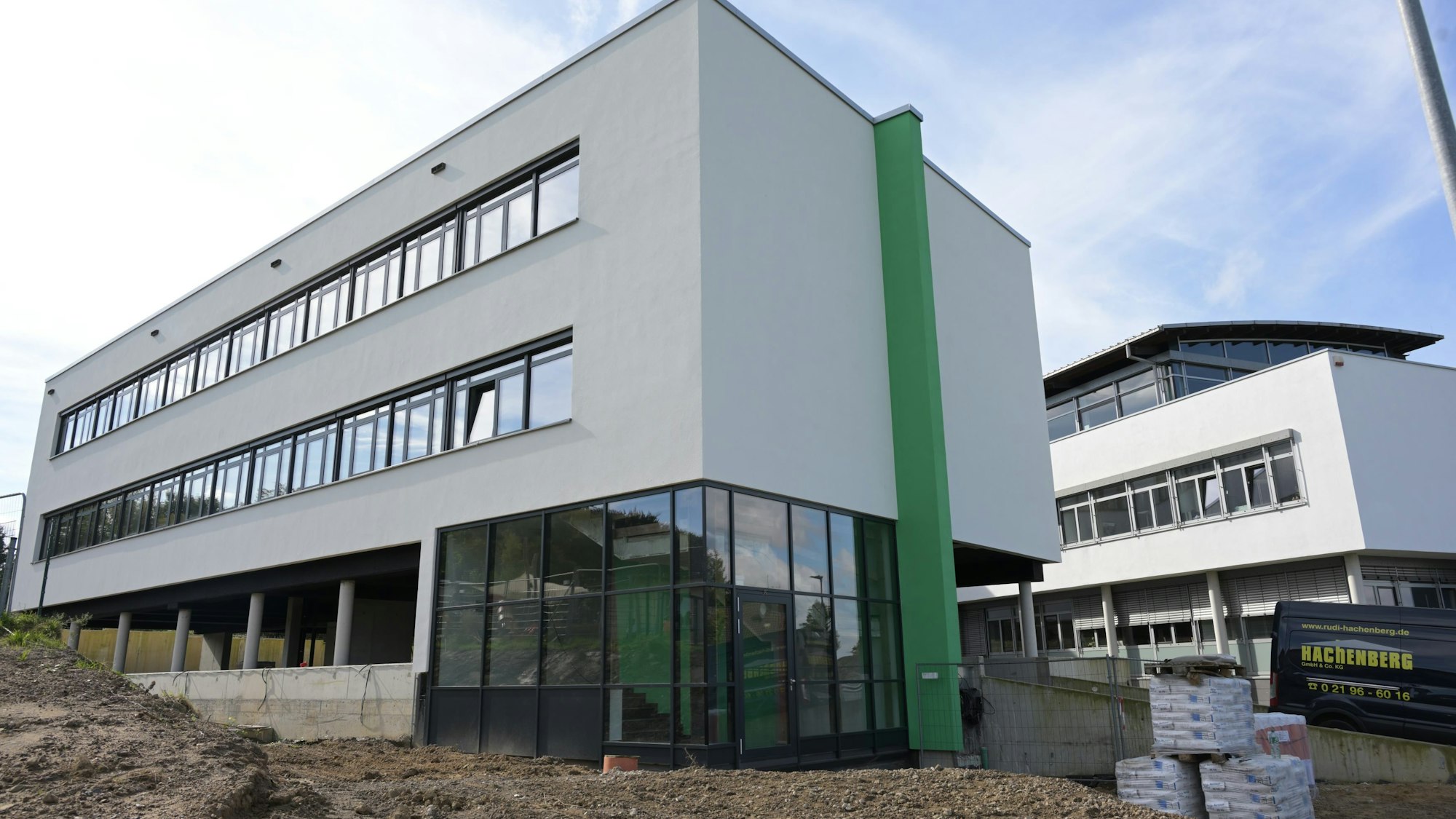 Im Vordergrund steht der Neubau, noch zwischen Erdhügeln. Im Hintergrund ist der Altbau zu sehen.