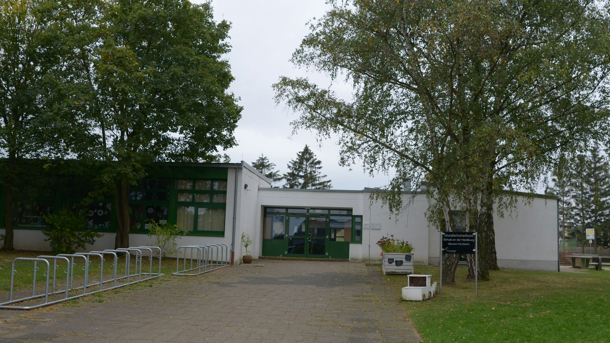 Ein Blick auf die Schule in Kirchheim, einen von Bäumen umgebenen Flachbau.
