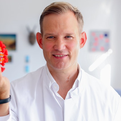 Professor Hendrik Streeck in seinem Büro in der Bonner Universitätsklinik mit dem Modell eines Virus
