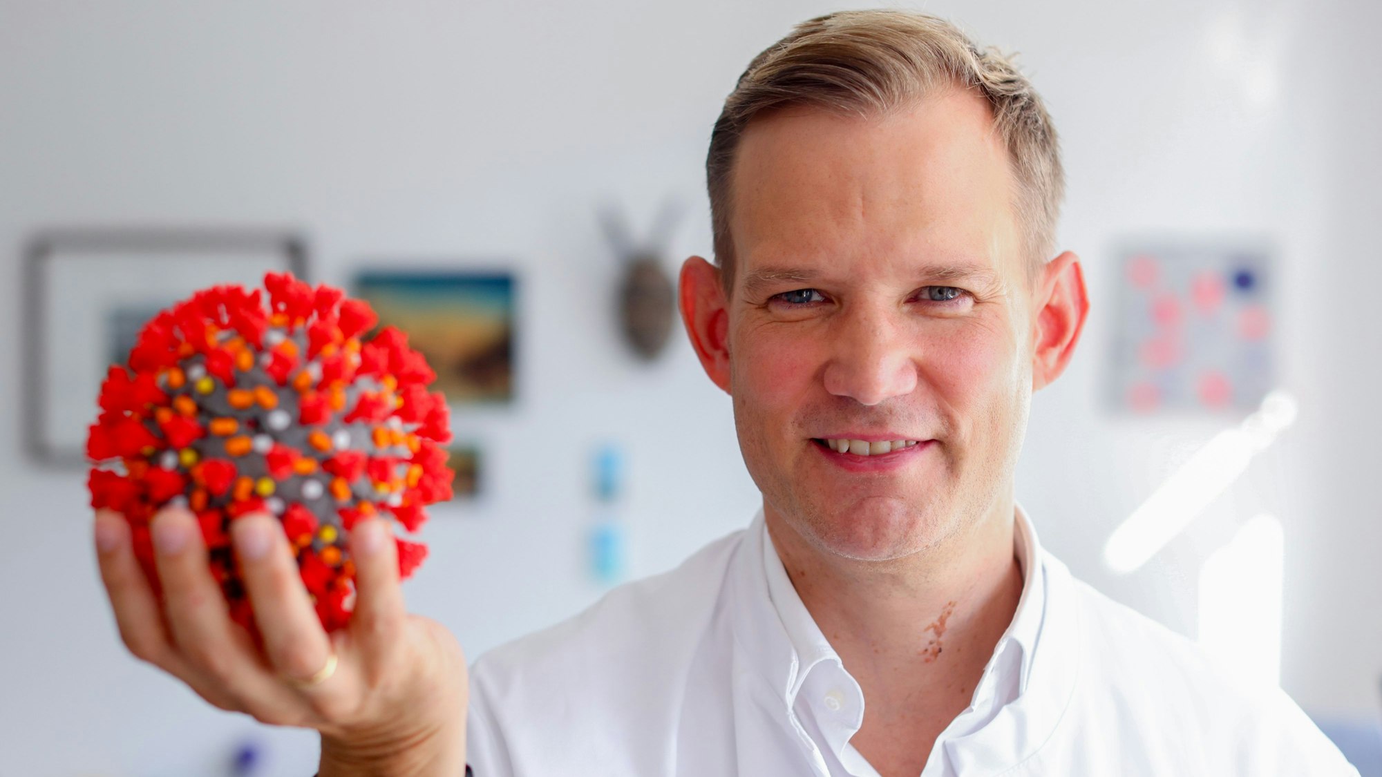 Professor Hendrik Streeck in seinem Büro in der Bonner Universitätsklinik mit dem Modell eines Virus