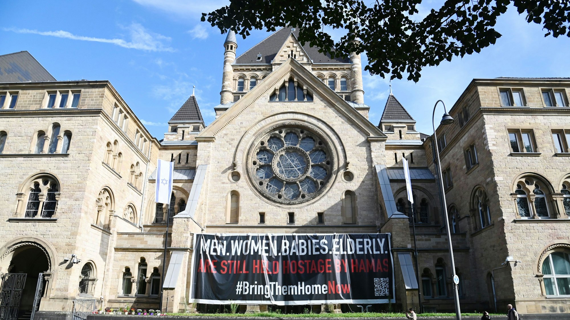 Synagoge Köln mit Plakaten und Blumen, die an den Terrorangriff erinnern.