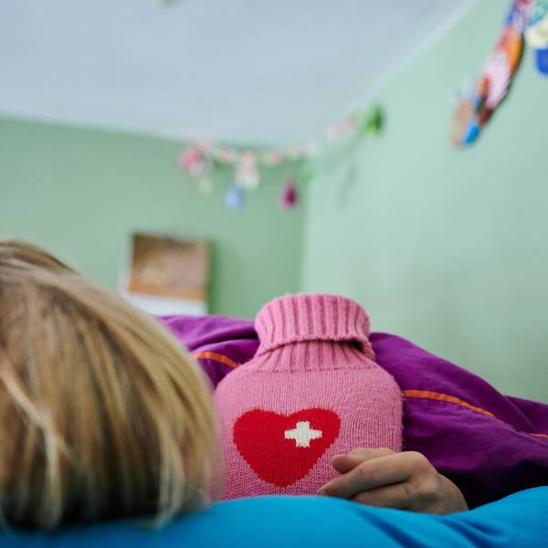 Ein Kind liegt mit Wärmflasche im Bett.
Wer eine Erkältung hat, braucht Ruhe.