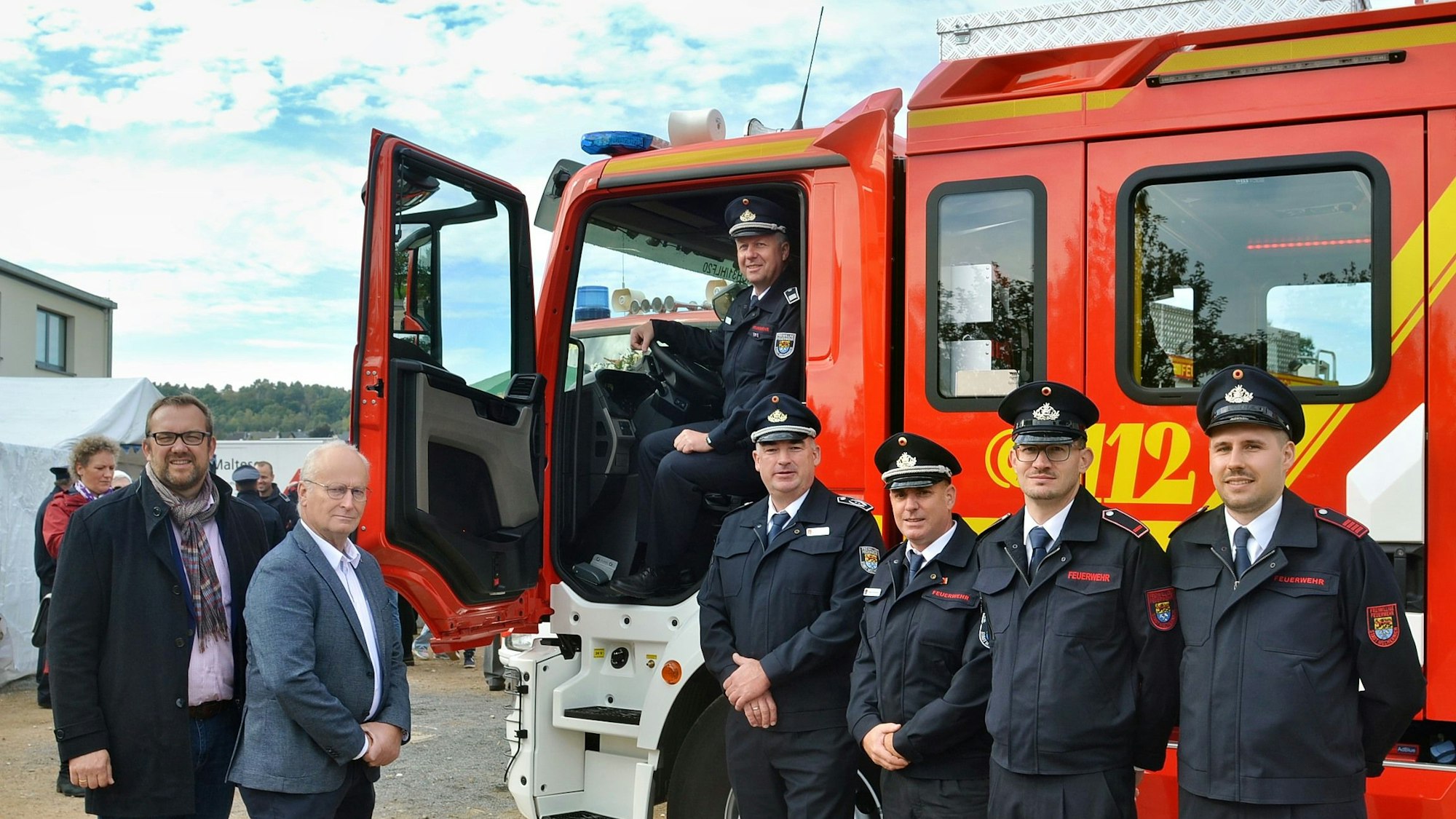 Feuerwehrmänner und Politiker stehen vor dem neuen Feuerwehrauto.