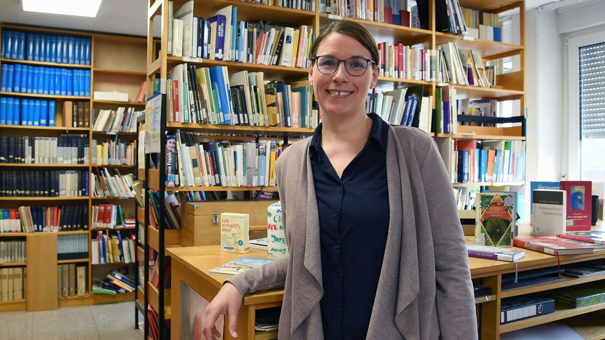 Eine junge Frau vor Bücherregalen.