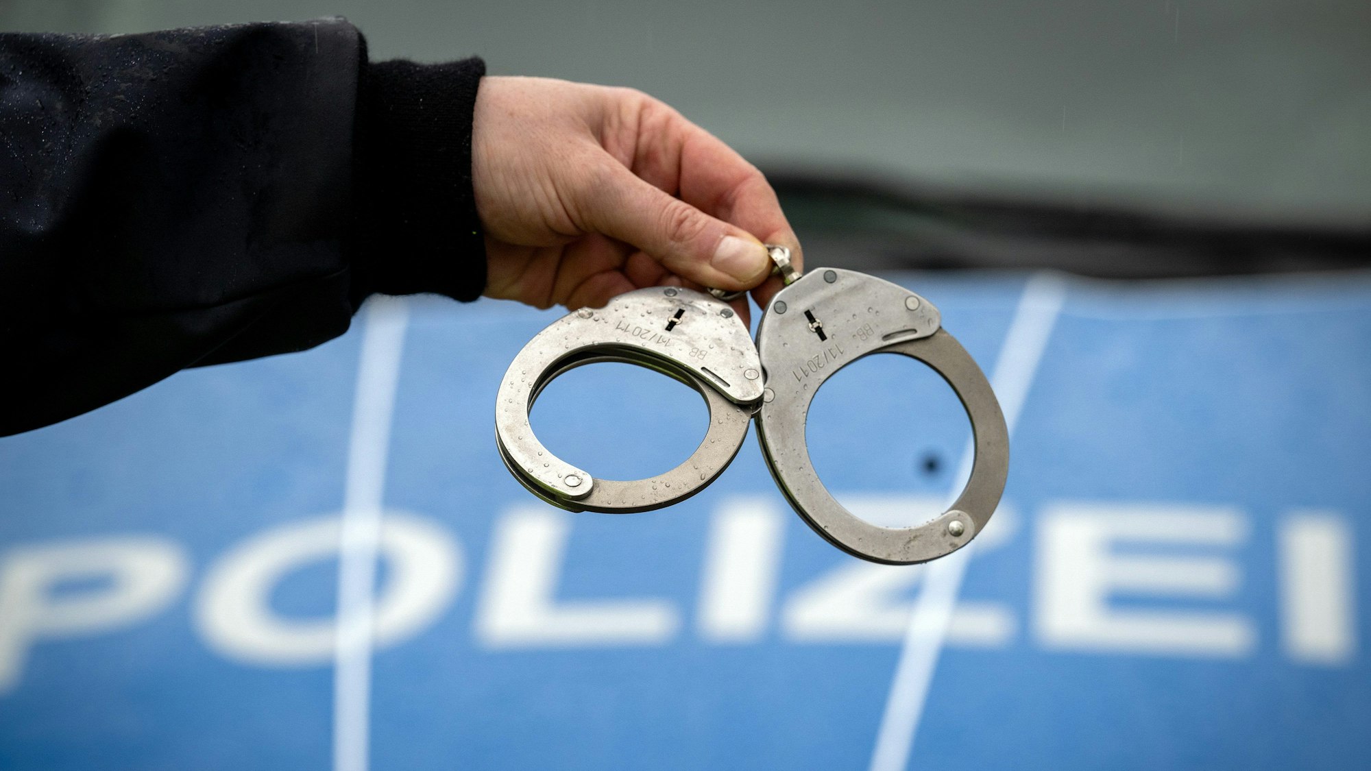 Ein Polizist hält ein Paar Handschellen.
