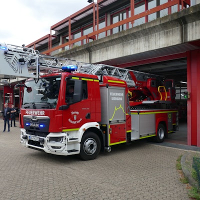Eine Drehleiter der Feuerwehr fährt aus einem Wachgebäude.