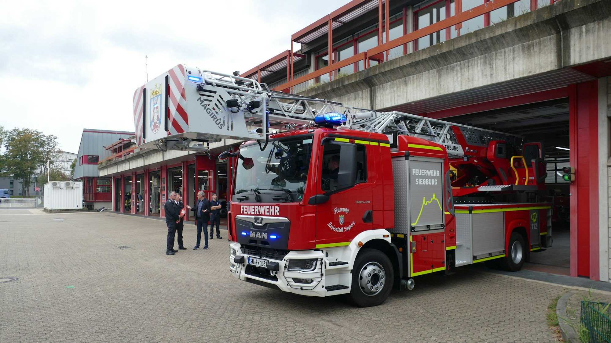 Eine Drehleiter der Feuerwehr fährt aus einem Wachgebäude.