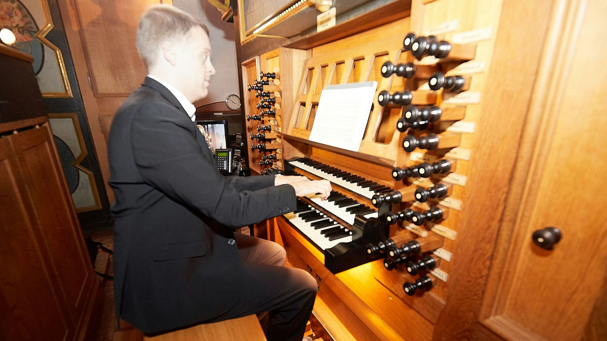 Eine Person im Anzug betätigt Tasten einer Orgel.