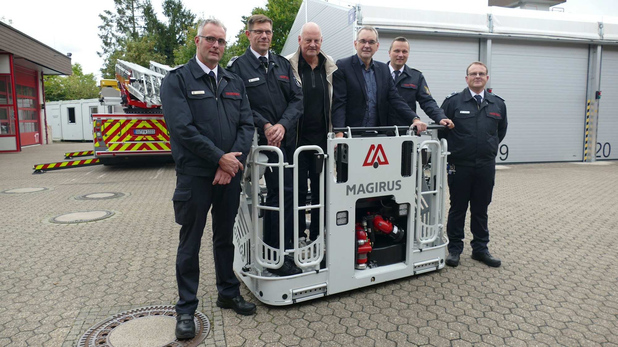 Sechs Männer stehen im und am Korb einer Drehleiter der Feuerwehr.
