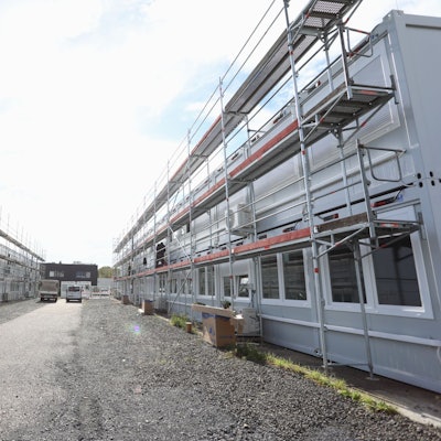 Graue Wohncontainer, die teilweise eingerüstet sind.