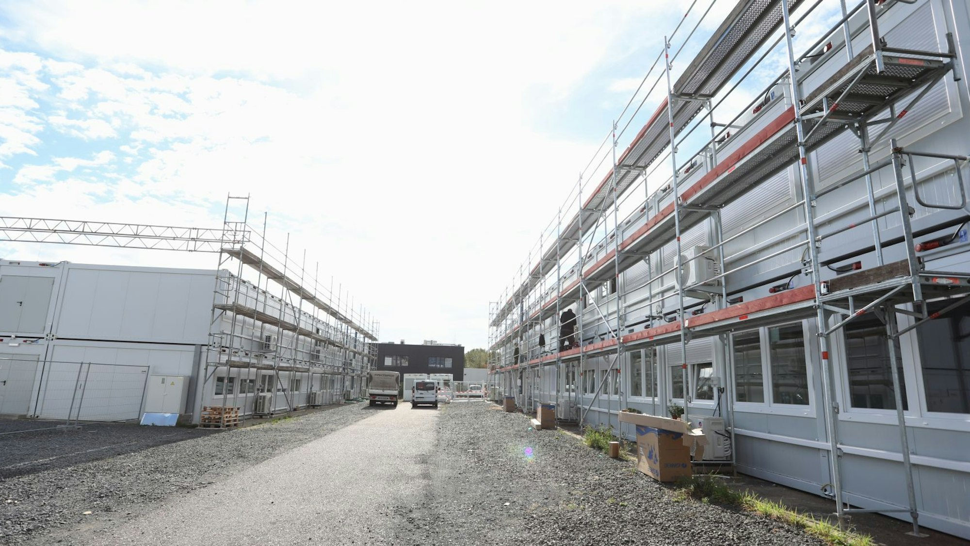 Graue Wohncontainer, die teilweise eingerüstet sind.