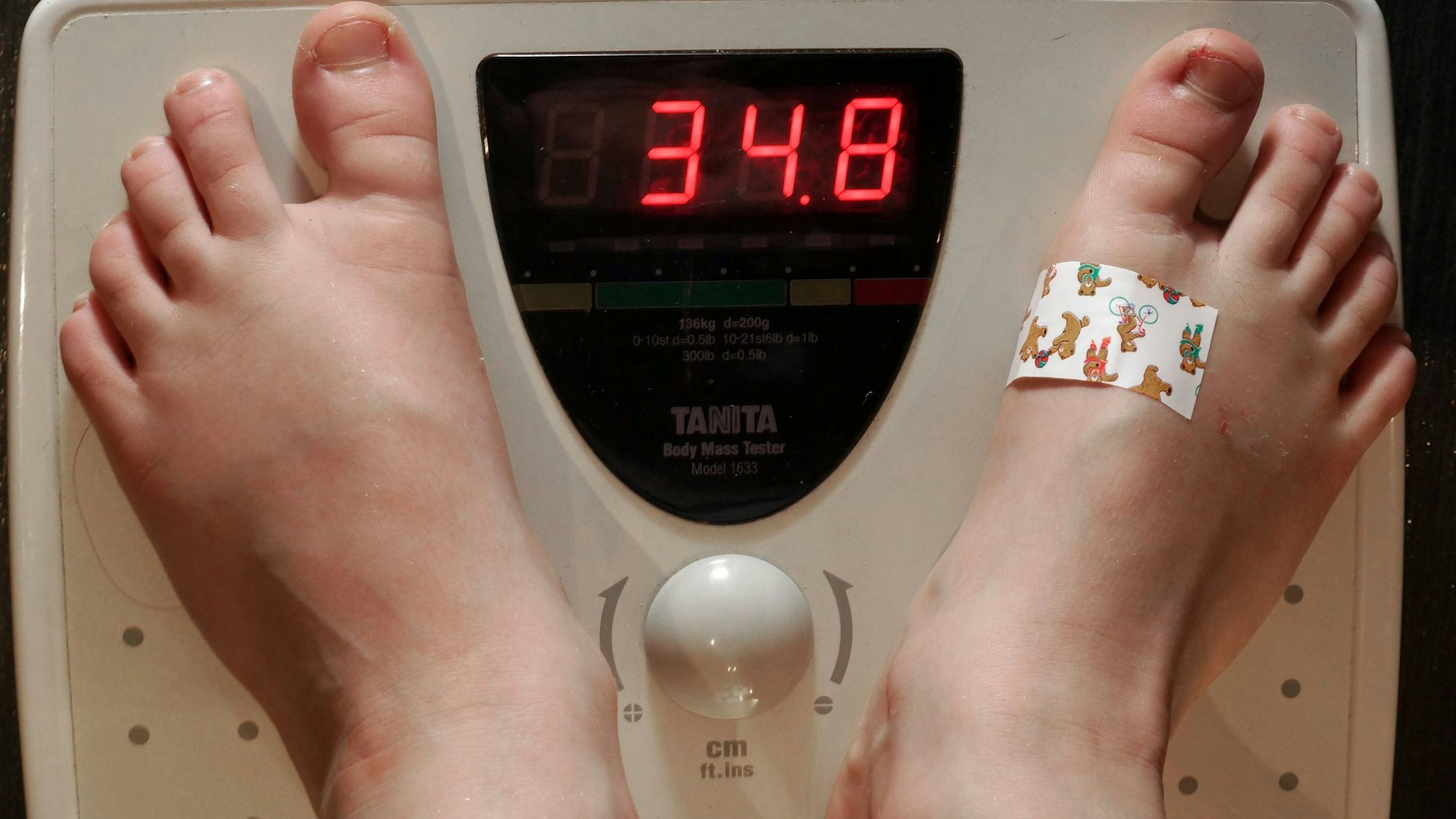 Ein siebenjähriges Schulkind steht auf einer Personenwaage. Die Waage zeigt ein Gewicht von 34,8 Kilogramm an, dies ist ein deutliches Übergewicht.