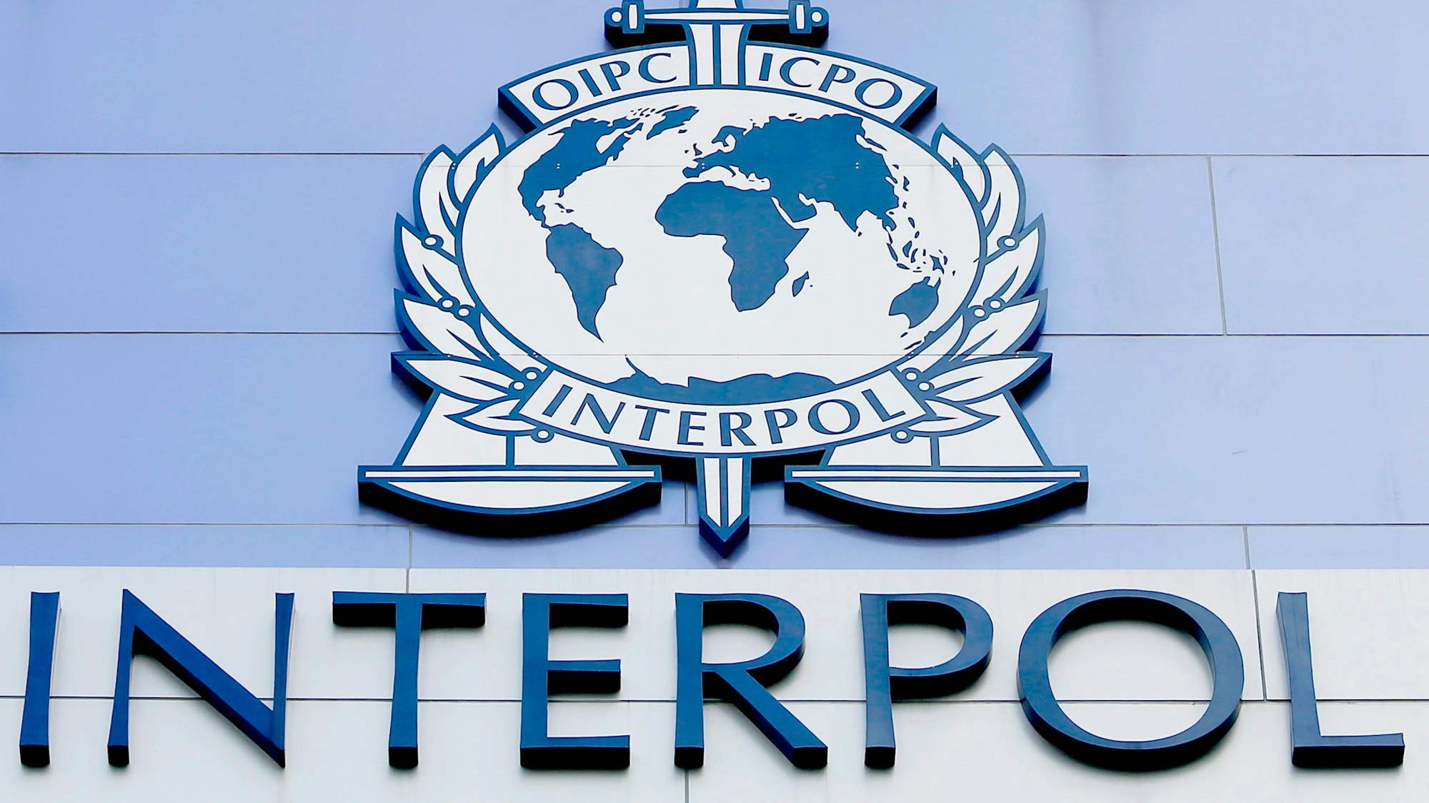 Das Emblem und den Schriftzug von Interpol auf der Fassade eines Interpol-Gebäudes in Singapur.