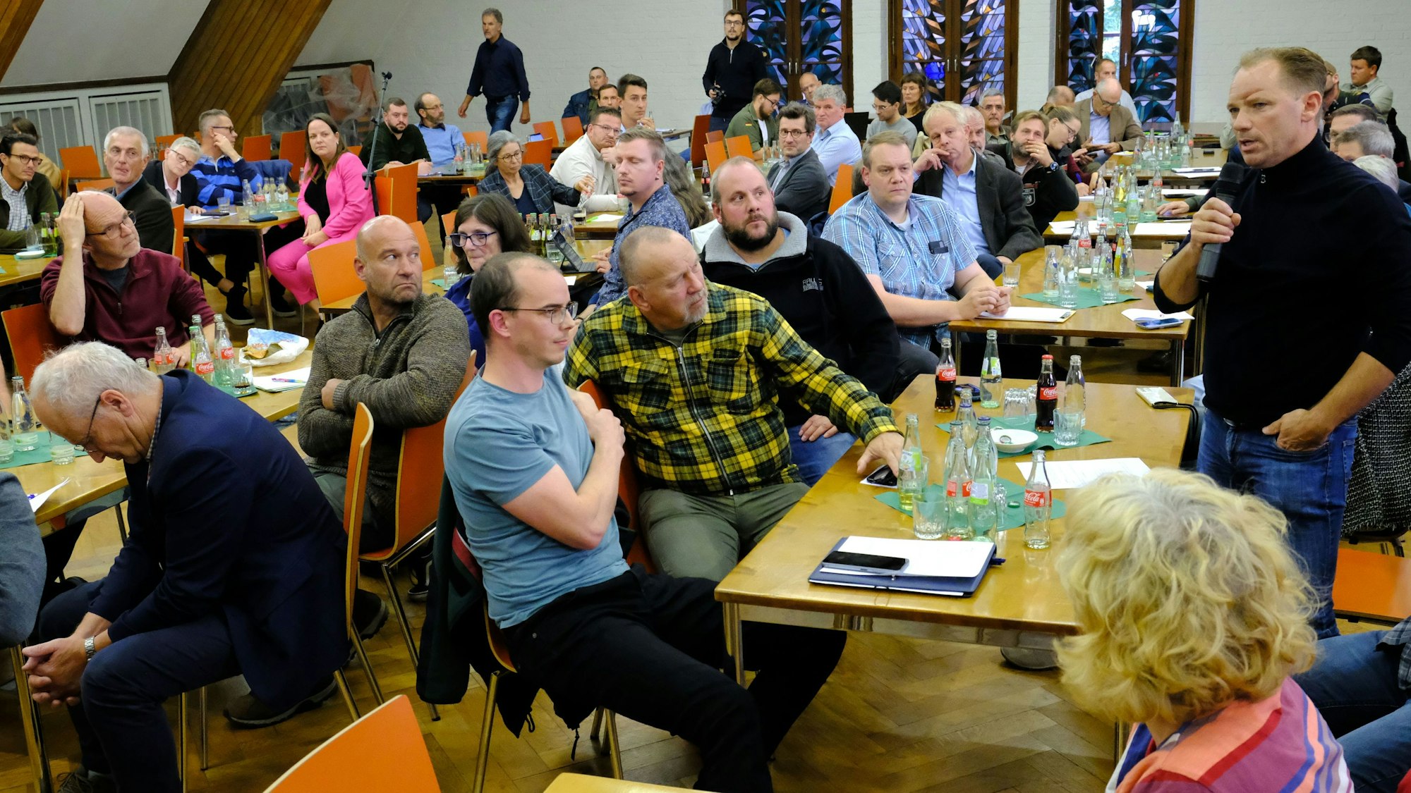 In der Aula der Landwirtschaftskammer in Düren sitzen zahlreiche Teilnehmer einer Diskussionsveranstaltung an Tischen.