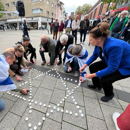 In Gedenken für die Opfer des Hamas-Pogroms vor einem Jahr legten Teilnehmer der Mahnwache auf dem Rathausvorplatz einen Davidstern aus Krezen.
