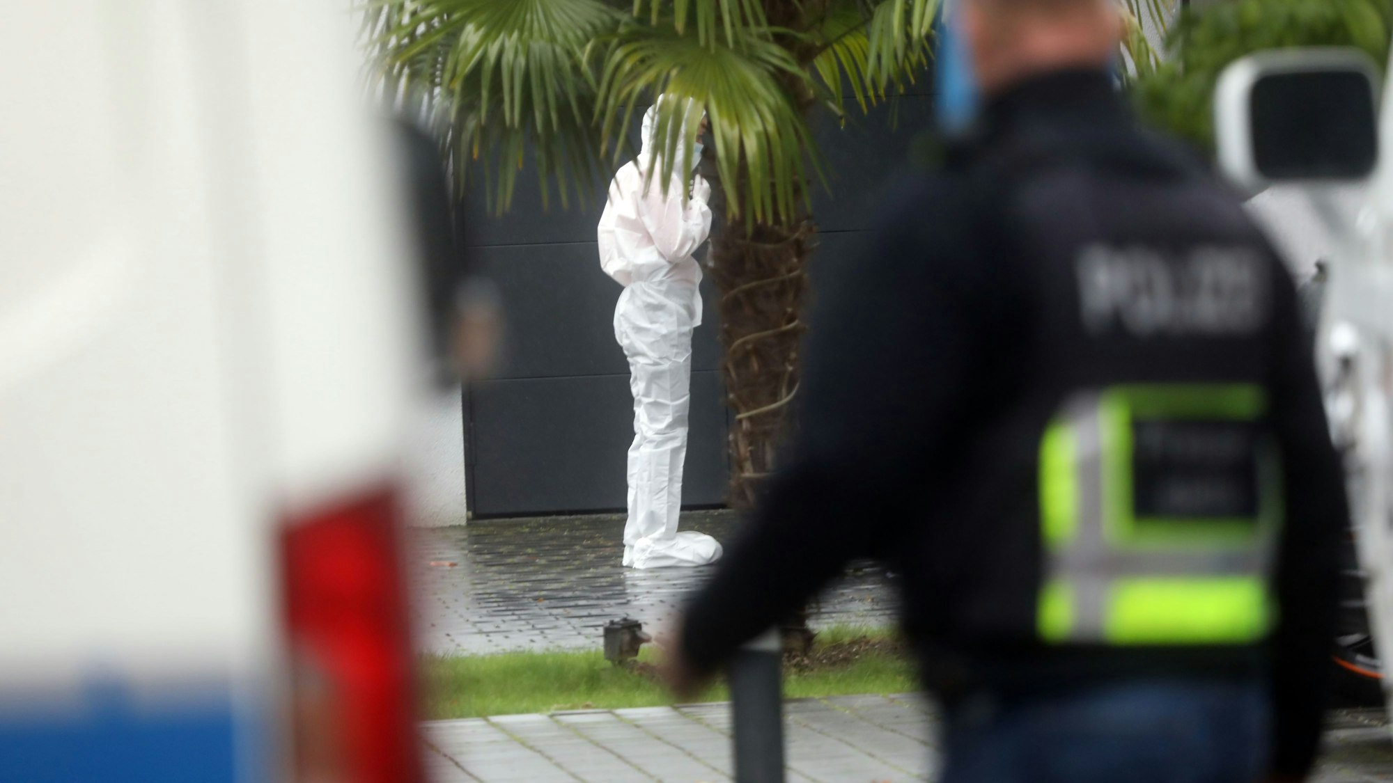 Ermittler in weißen Overalls untersuchen den Tatort im Villenviertel.