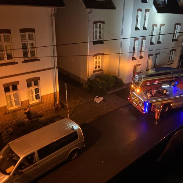 Feuerwehrautos stehen im Dunkeln vor einem Gebäude.