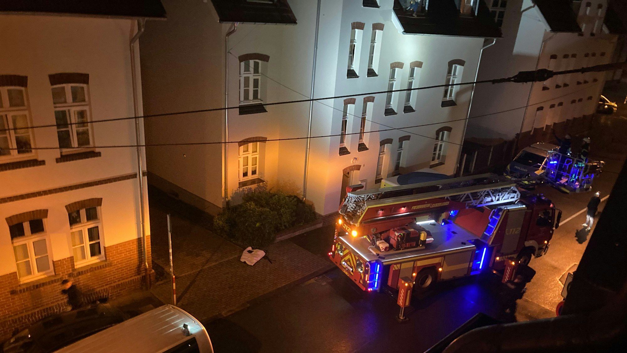 Feuerwehrautos stehen im Dunkeln vor einem Gebäude.