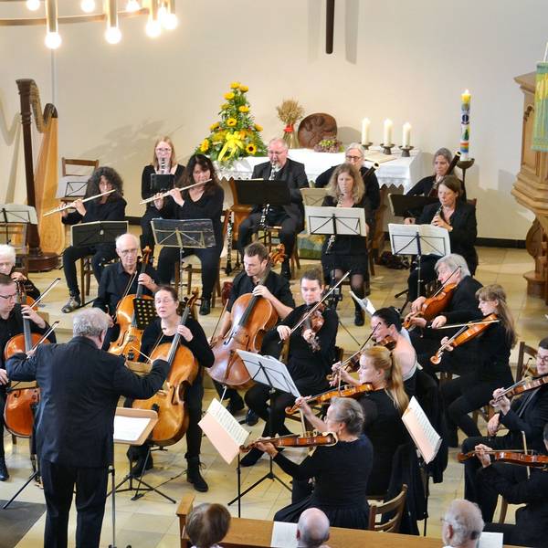 Das Orchester spielt im Altarraum, der mit Blumen und Kerzen geschmückt ist.