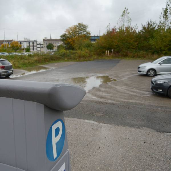 Ein Blick auf den Parkplatz mit einer Reihe freier Plätze, im Vordergrund ein Parkscheinautomat.