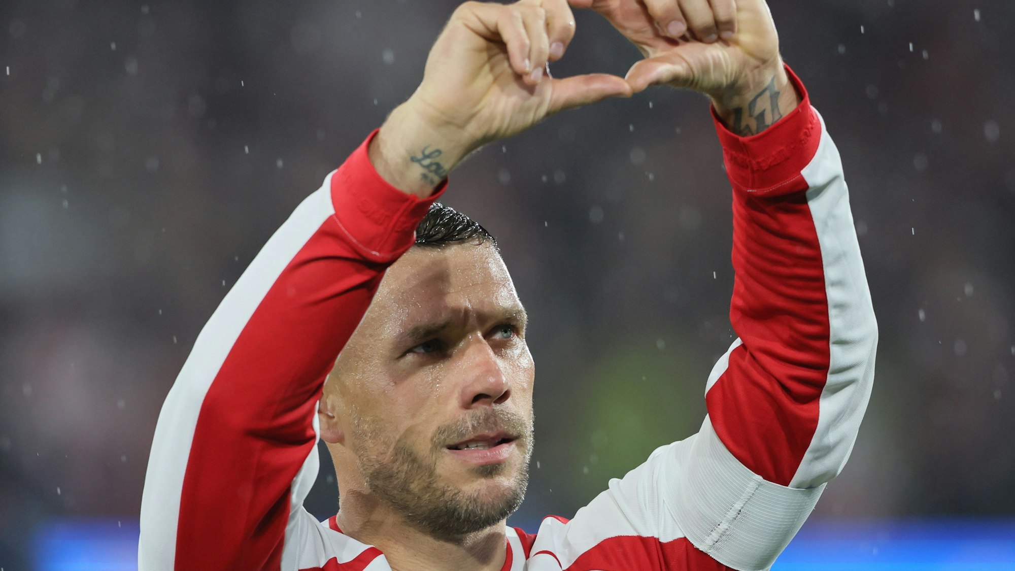 Lukas Podolski formt mit seinen Händen ein Herz.