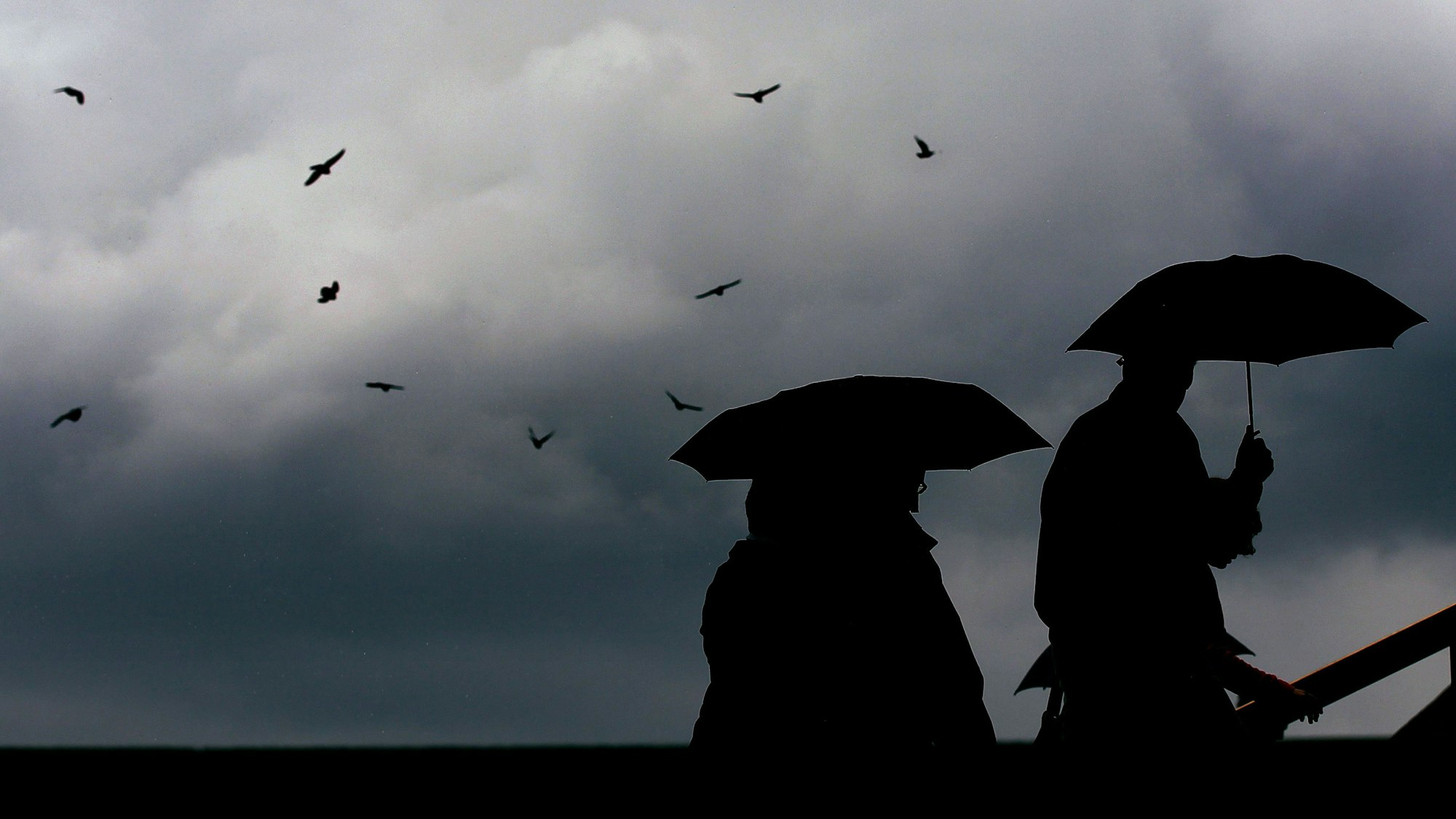 Passanten gehen mit Regenschirmen durch die Innenstadt von Köln. (Archivbild)