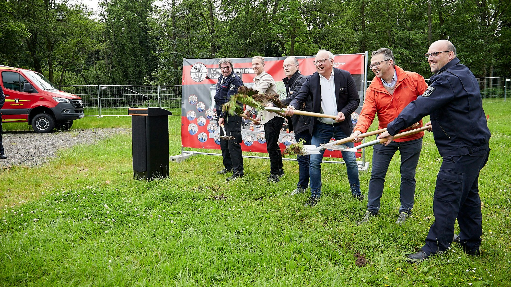 Mehrere Personen beim symbolischen Spatenstich auf einer Wiese.
