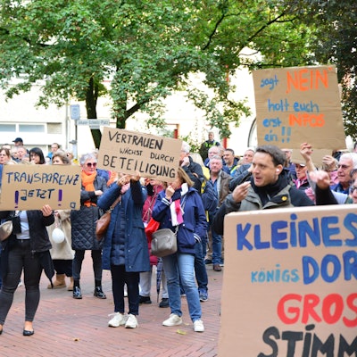 Bürger halten vor dem Frechener Rathaus Transparente hoch.