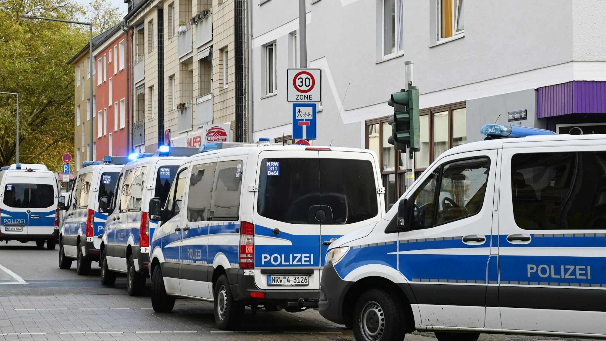 Zahlreiche Einsatzfahrzeuge der Polizei parken in der Franz-Geuer-Straße in Köln.
