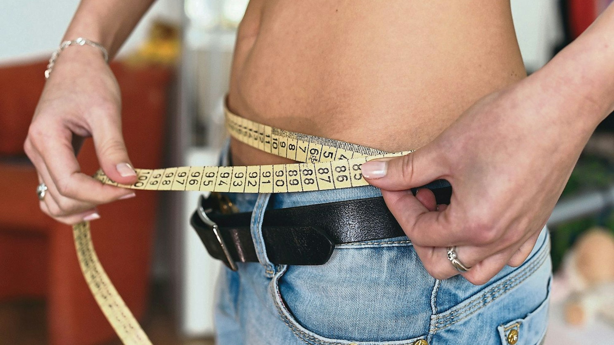 Eine junge Frau mit einem Zentimetermaß um den Bauch, fotografiert am 10.04.2014 in Berlin. Foto: Jens Kalaene/dpa (zu lsw Berichtersttung über Essstörungen vom 27. und 28.09.2014) +++ dpa-Bildfunk +++