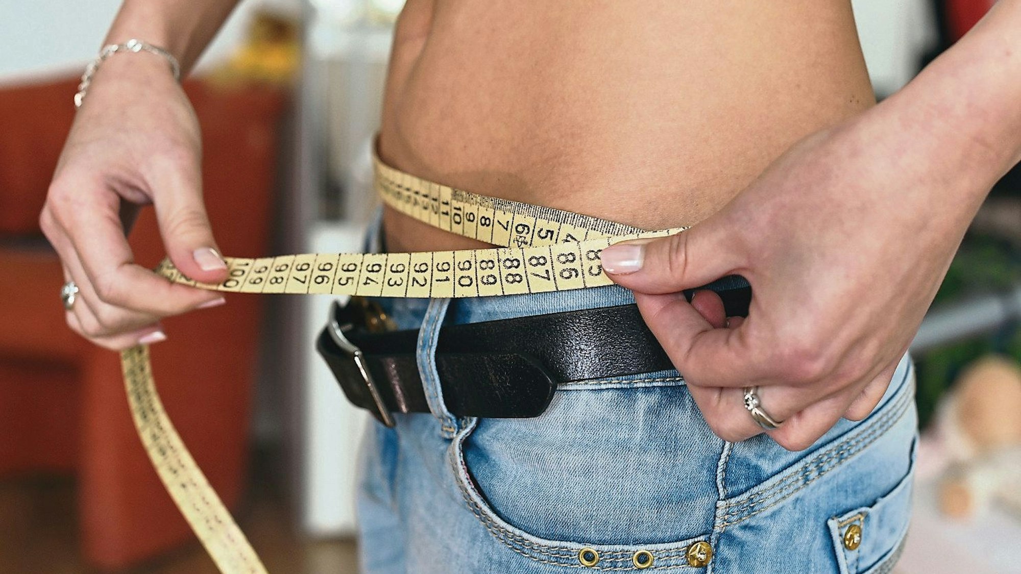 Eine junge Frau mit einem Zentimetermaß um den Bauch