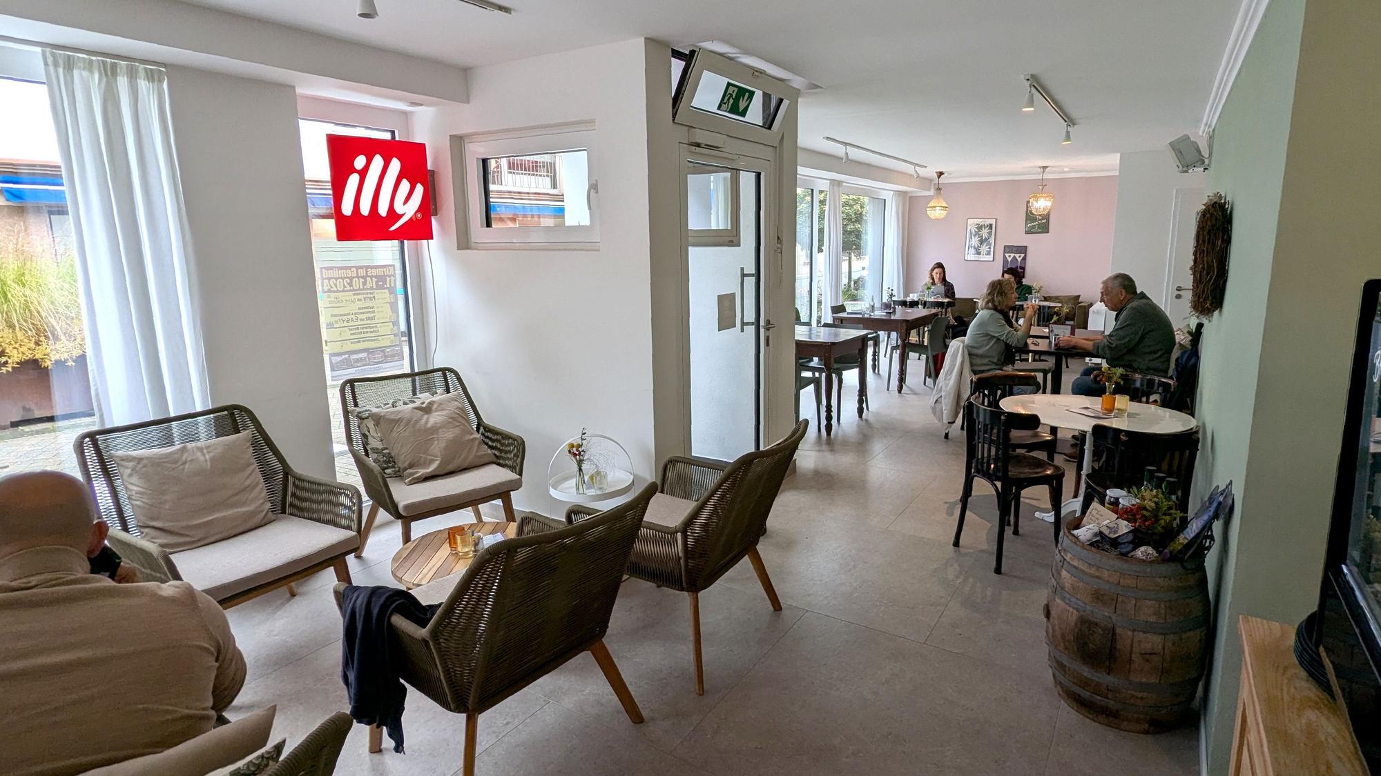 Blick in den Gastraum der Café-Bar Lou in Gemünd, wo ein paar Gäste an Tischen sitzen.