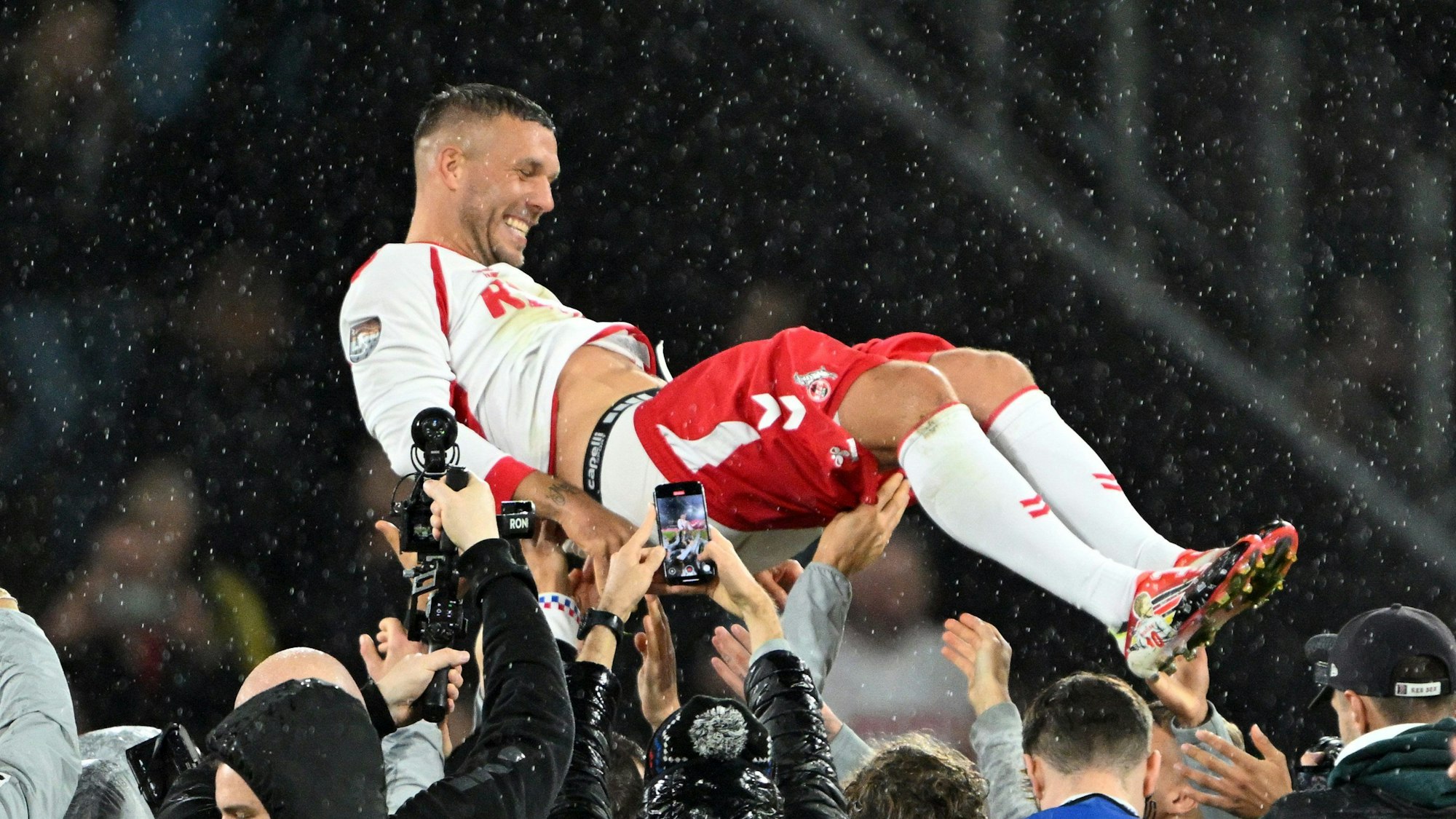 10.10.2024, Nordrhein-Westfalen, Köln: Fußball: Abschiedsspiel von Lukas Podolski beim 1. FC Köln, Mitspieler werfen Lukas Podolski in die Höhe. (zu dpa: «Rückkehr erwünscht: Köln umwirbt Kultfigur Podolski») Foto: Federico Gambarini/dpa +++ dpa-Bildfunk +++