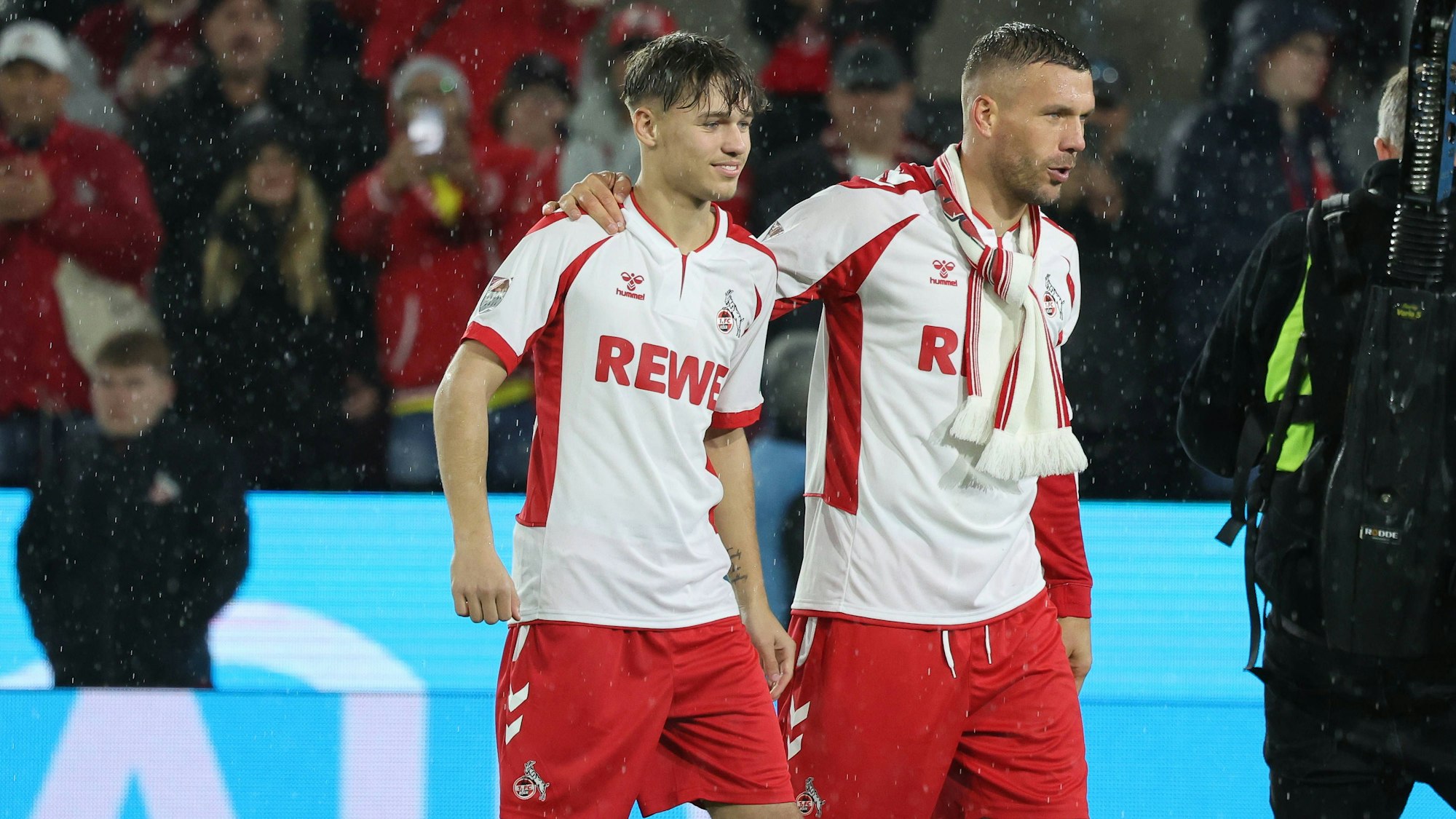 Lukas Podolski und Sohn Louis beschreiten Arm in Arm das Spielfeld von Müngersdorf.