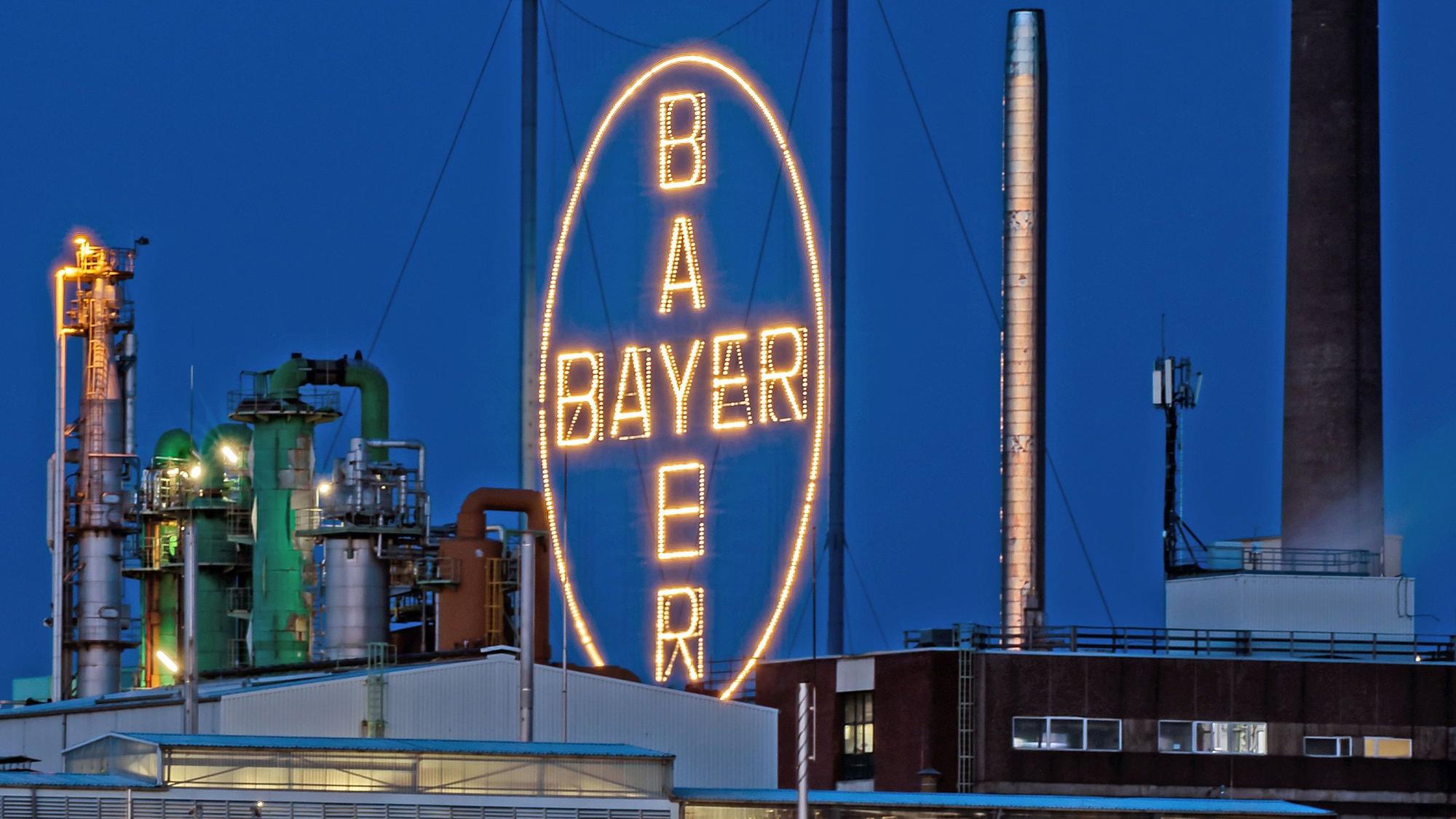 Das Bayer Kreuz, das Logo des Unternehmens, leuchtet auf dem Werksgelände von Bayer in Leverkusen, gegenüber dem Rheinufer in Köln.