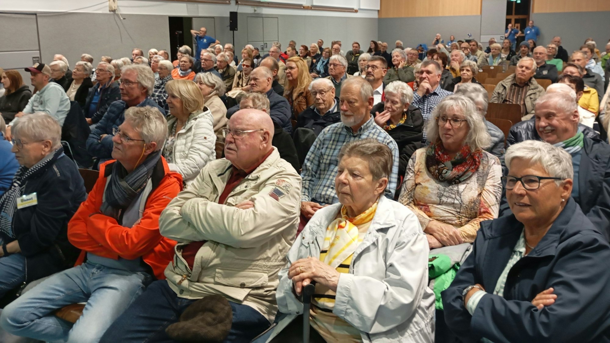 Das Bild zeigt eine Mehrzweckhalle, die mit Besuchern gefüllt ist.