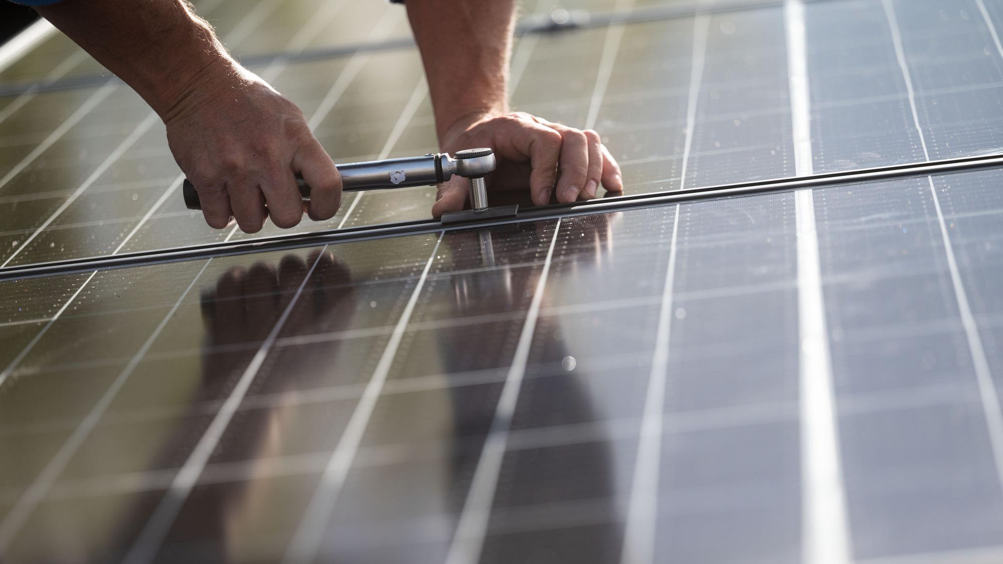 Ein Handwerker montiert ein Solarmodul.