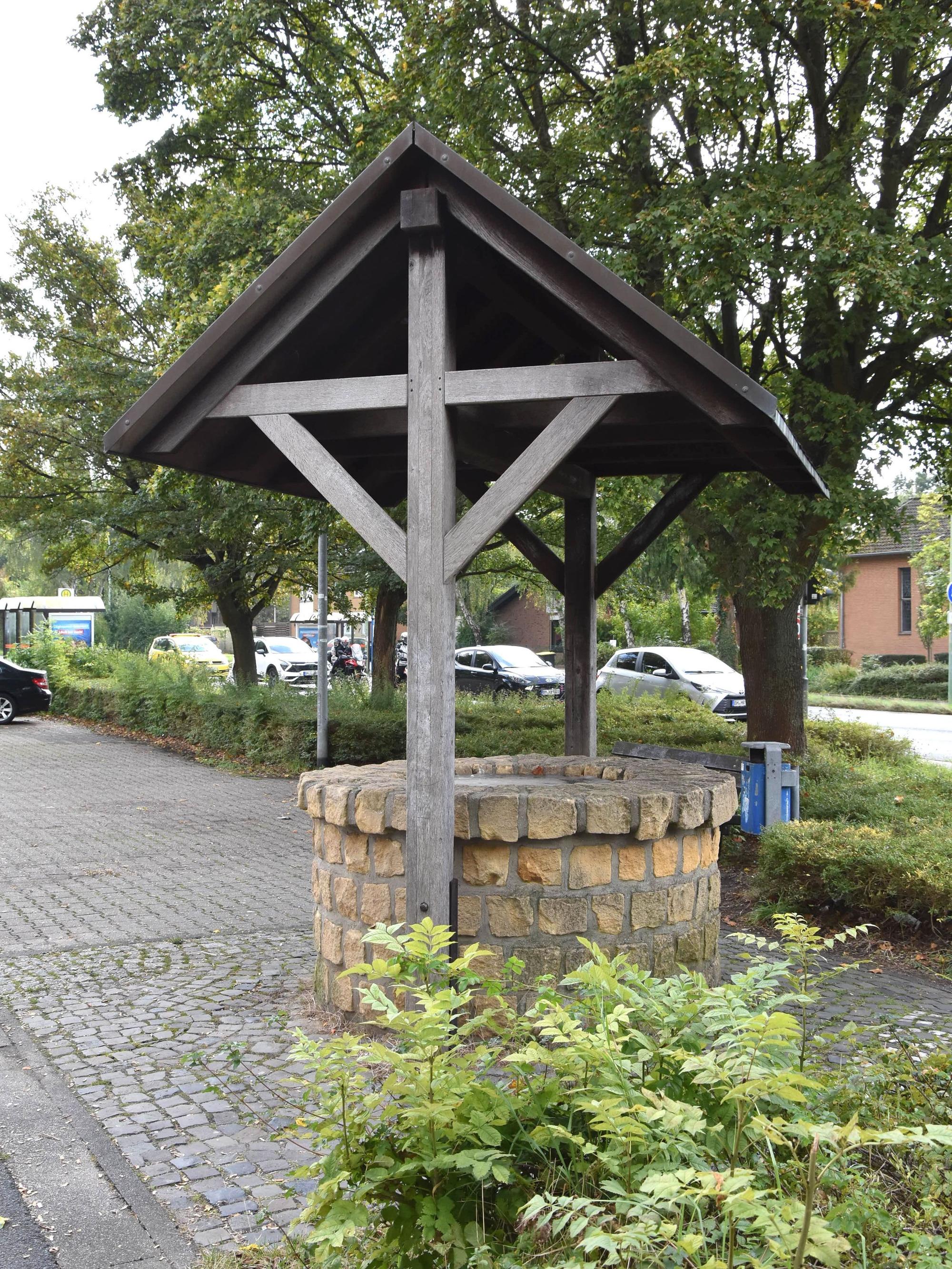 Das Bild zeigt einen Brunnen an einem Parkplatz.