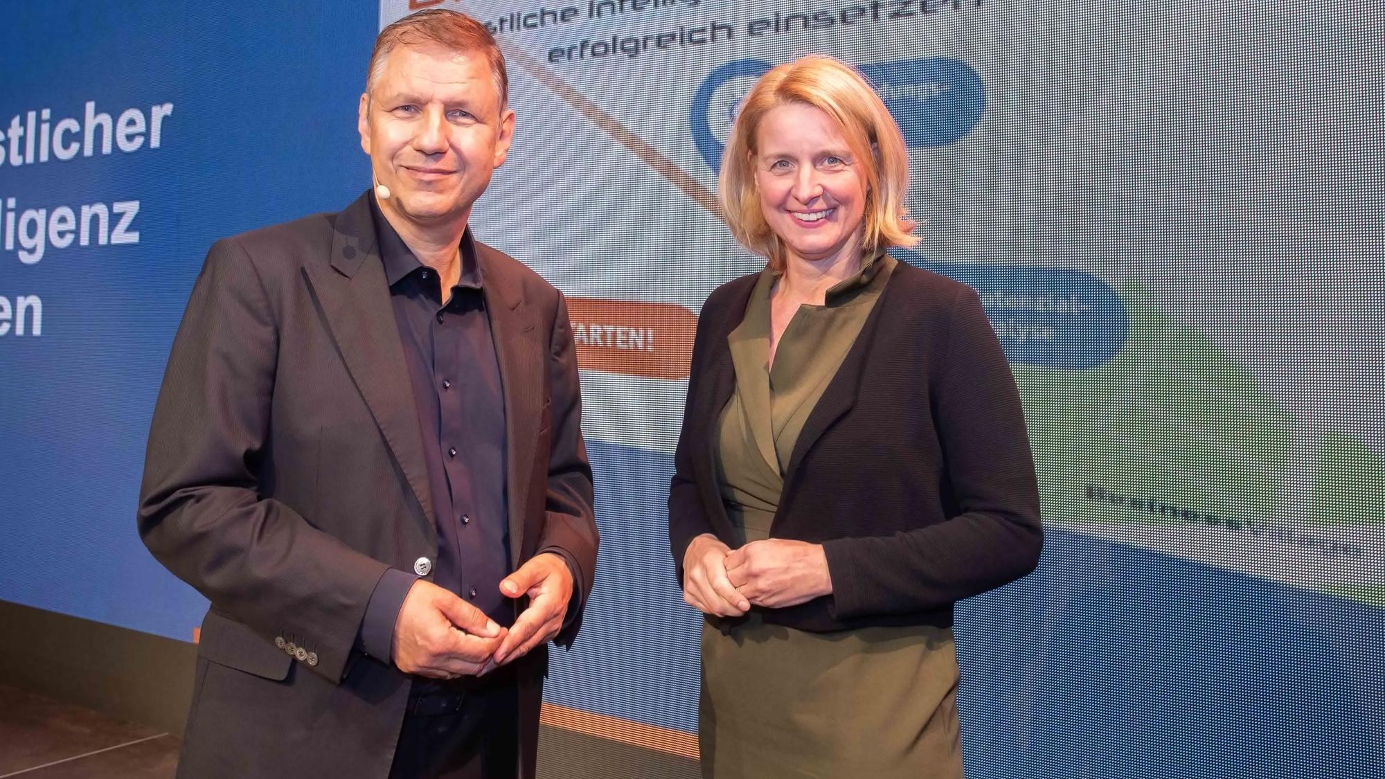 Eine Frau und ein Mann stehen vor einer Präsentationswand