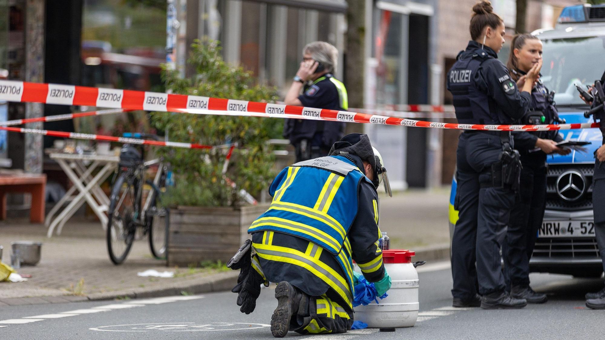 ARCHIV - 30.06.2024, Nordrhein-Westfalen, Bochum: Polizisten sind im Einsatz vor einem Bochumer Café, nachdem bei einem Angriff mit einer säurehaltigen Flüssigkeit im Außenbereich des Cafés mehrere Personen verletzt wurden.