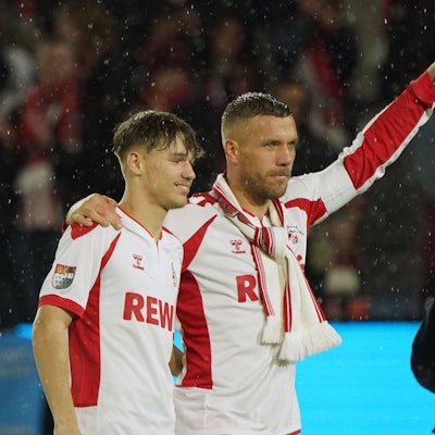 Ein seltenes Bild: Lukas Podolski steht zusammen mit Sohn Louis auf dem Rasen von Müngersdorf. Beim Abschiedsspiel in Köln spielten Vater und Sohn auch einige Minuten zusammen im FC-Sturm.
