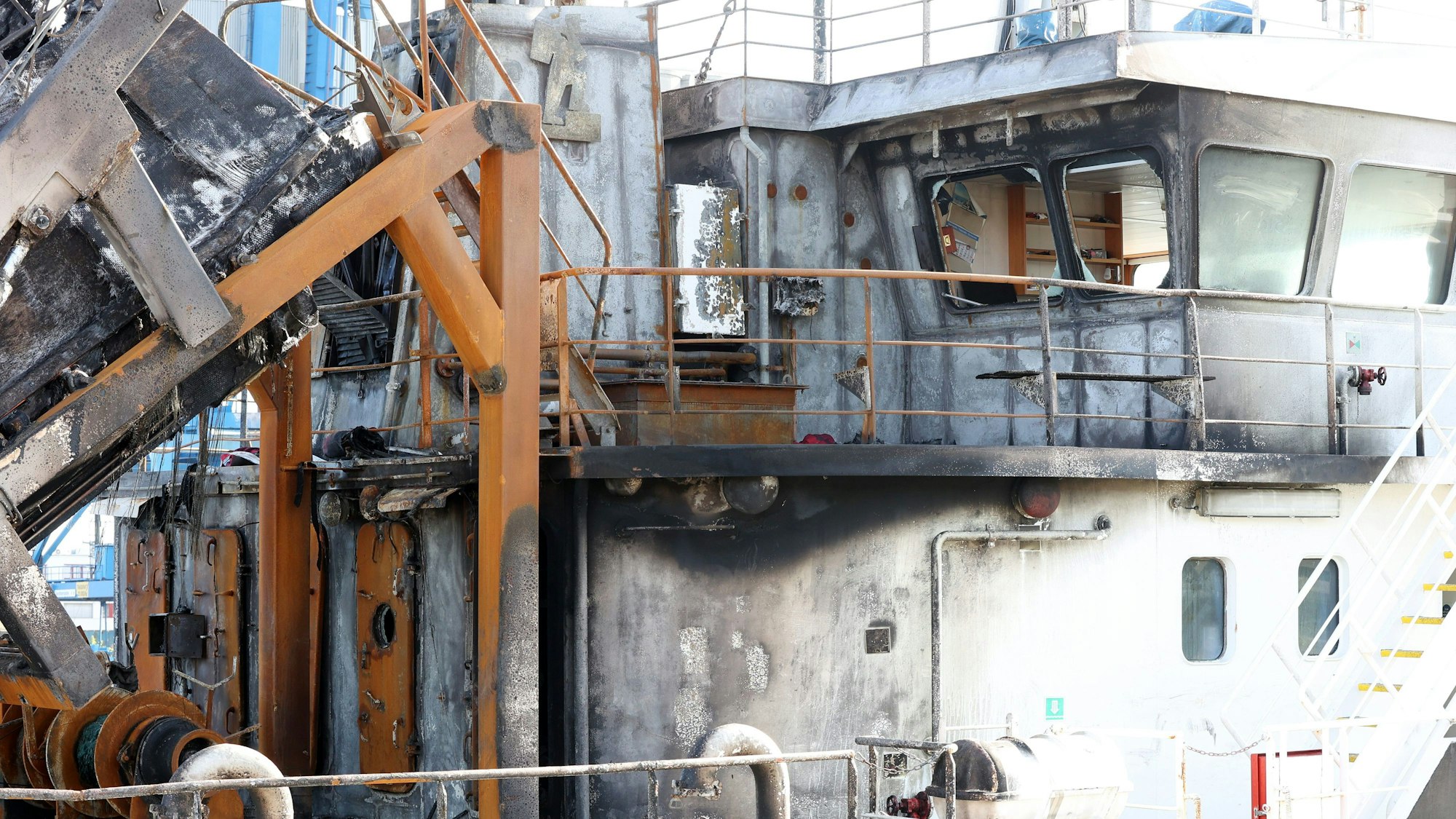 Das Tankschiff „Annika“ liegt am Überseehafen in Rostock. Das Schiff weist viele Schäden durch den Brand auf. Wände und Stahlteile sind schwarz, die Scheiben der Kabine geborsten.