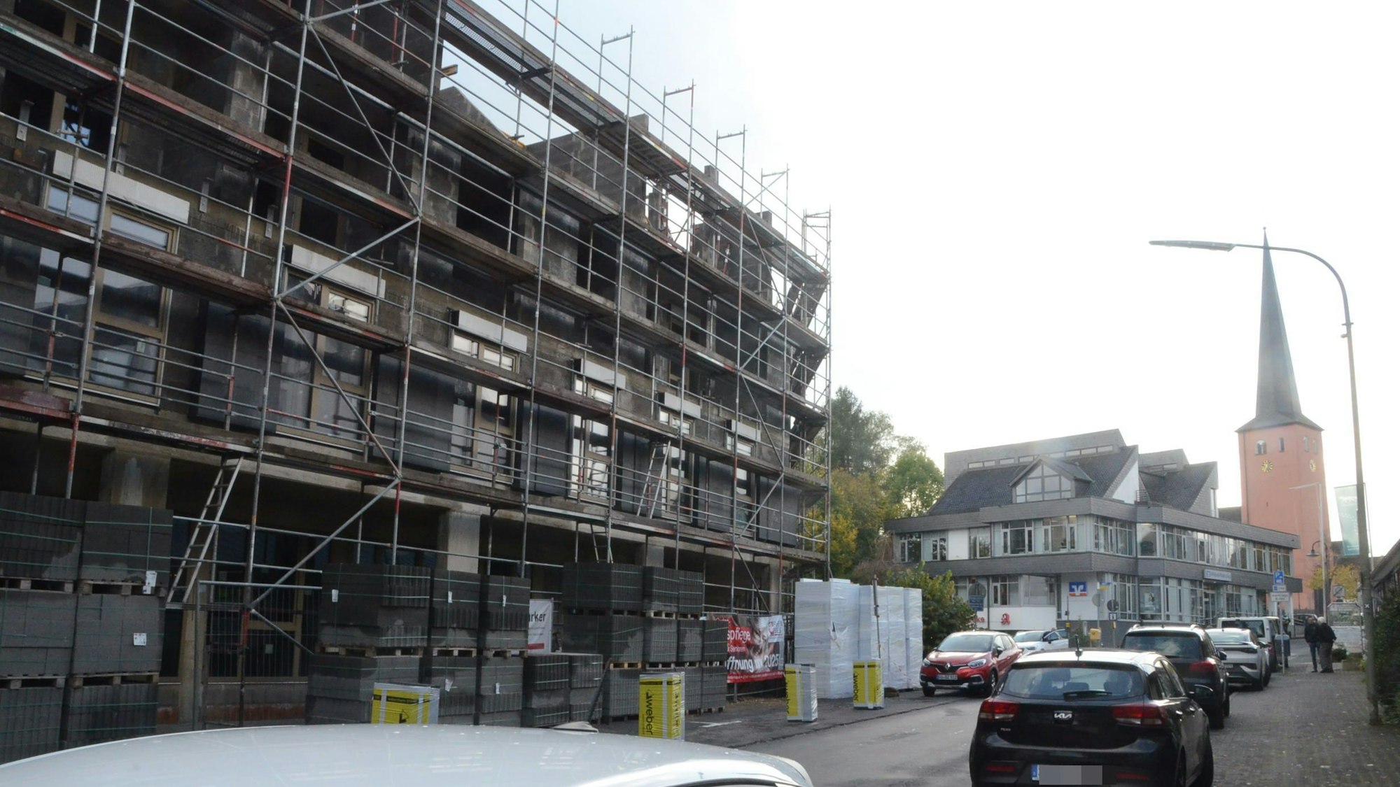 Der Rohbau für einen größeren Wohn- und Geschäftskomplex. Im Hintergrund ist der Turm einer nahen Kirche zu sehen.