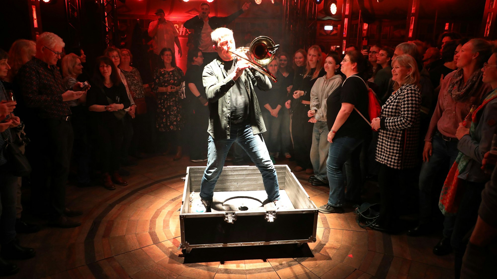 Ex-Wise-Guy Clemens Tewinkel steht mit Posaune im Scheinwerferkegel in einer Transportbox.