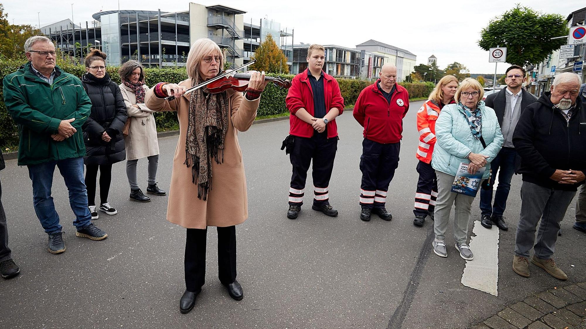 Das Bild zeigt Nicole Besse, wie sie Geige spielt. Um sie herum stehen Menschen, die der Stolpersteinverlegung beiwohnen.